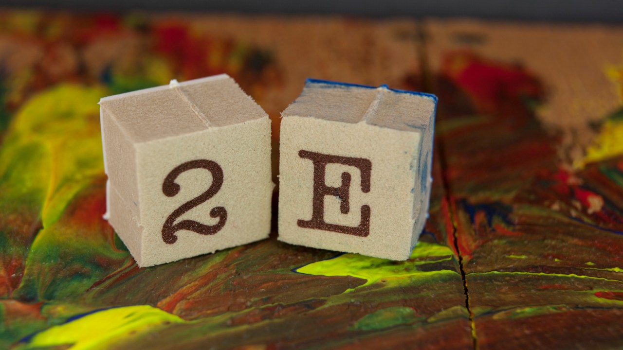two child's wooden blocks one showing 2 one showing E