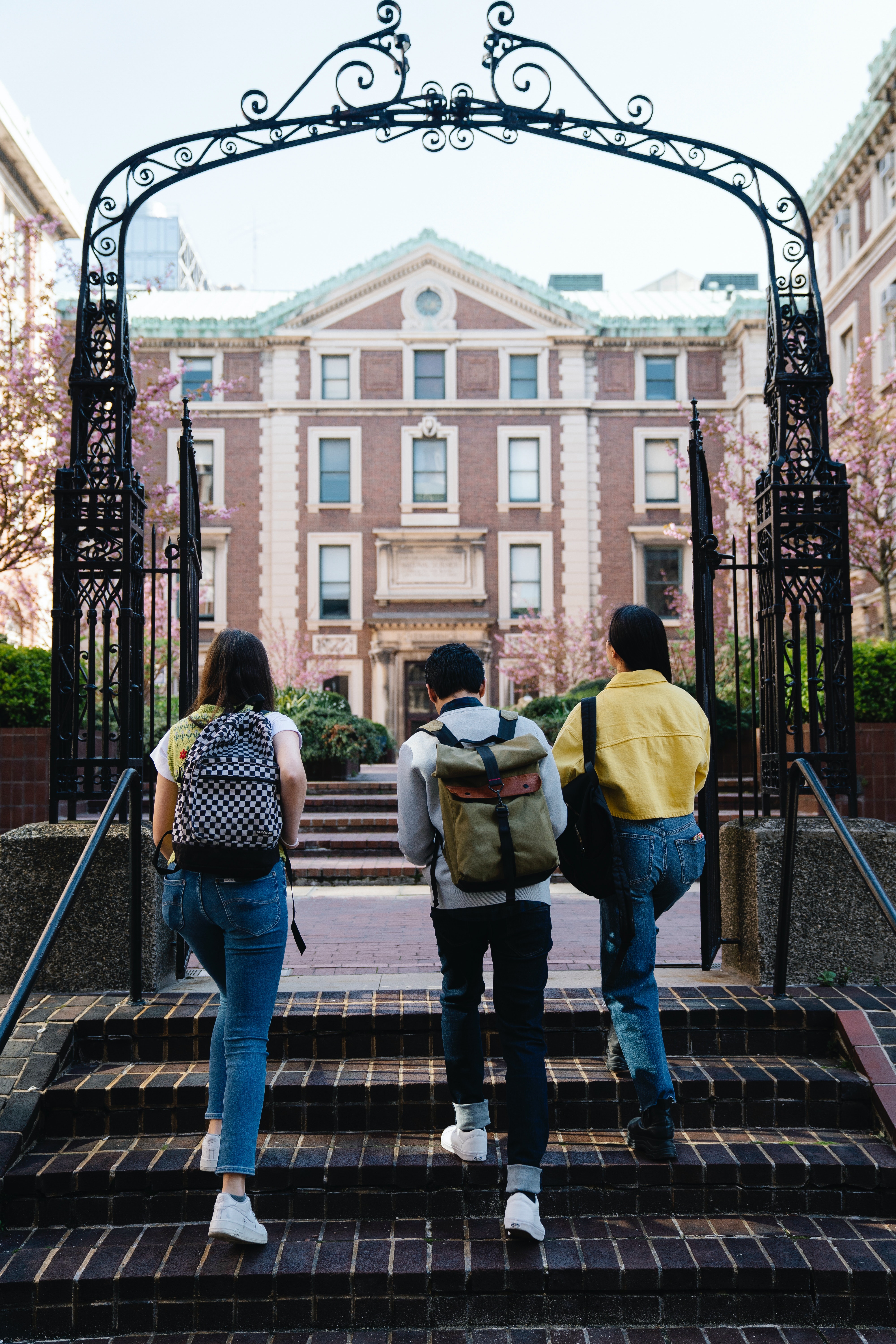 three students walking upstairs to a college building